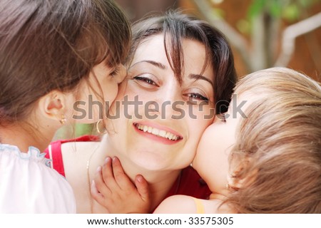 Girls kissing smiling mothers cheeks closeup photo