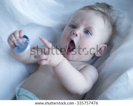 Picture of baby playing with pacifier  in high-key