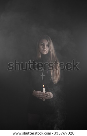Lonely young woman holding a candle in a smoke