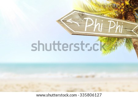 Phi Phi wooden sign and blurry exotic beach background. Tropical landscape with coconut palm tree and white sand beach. Paradise design banner background.