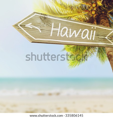 Hawaii wooden sign and blurry exotic beach background. Tropical landscape with coconut palm tree and white sand beach. Paradise design banner background.