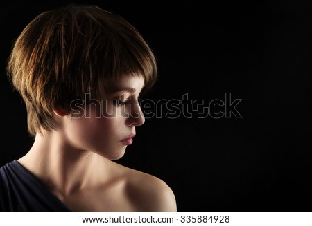 Side portrait of a young woman with short brown hair on a black background Royalty-Free Stock Photo #335884928