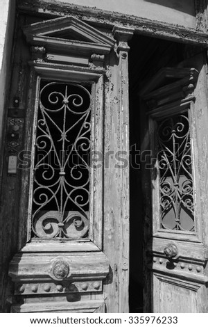 Opened door with bell buttons. Entrance to the old residential building in the centre of Lisbon (Portugal). A game of light and shadow. Aged photo. Black and white.