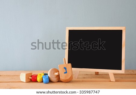 image of jewish holiday Hanukkah with wooden colorful dreidels (spinning top) with chalkboard background
