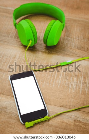 Green headphone with a back smartphone on wood desk