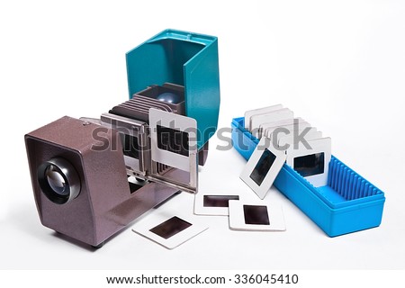 Retro cine-projector on white background. Old projector for displaying of slides. Big blue box with photo slides for displaying on projector and several slides on white near blue box and projector.
