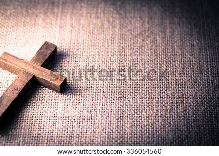 An aerial view of a holy wooden Christian cross on a burlap background.