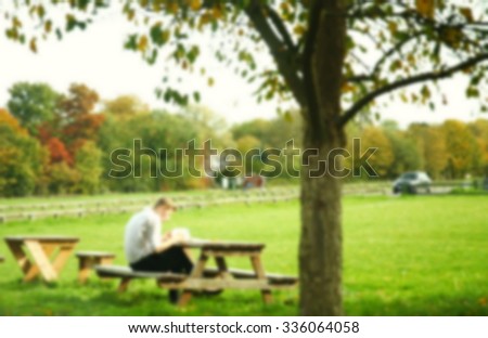 The blurry photo  of man and woman sit on the wooden chair under the tree represent the people activity concept related idea.