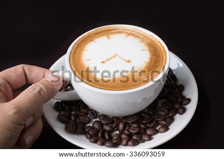 Cappuccino or latte coffe in a white cup with heart shaped foam on wooden board