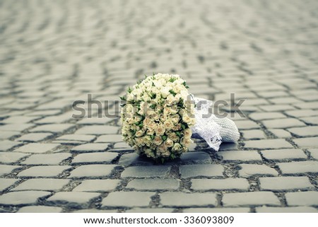 Closeup view of one beautiful fresh bright white yellow big wedding bouquet of rose flowers lying on grey road outdoor on natural background, horizontal picture