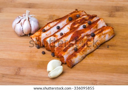 Photo closeup traditional ukrainian preserved salted spicy red pepper lard bacon pork fat slices with garlic and allspice berries on wooden cutting board on timber background, horizontal picture
