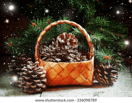 Christmas or New Year composition with wicker basket, pine cones and spruce branches on an old wooden background in rustic style, selective focus