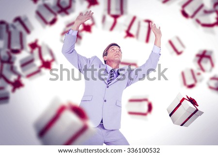 Scared businessman with hands raised against white and red gift box