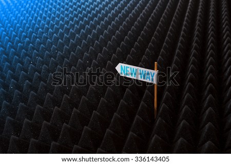 white directional sign saying NEW WAY on bumpy black background