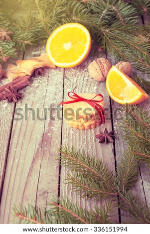 Christmas decor on rustic wooden table. Nuts, fir tree, ginger cookies, cinnamon, anis in Christmas composition. Toned image