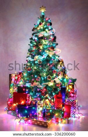 Decorated Christmas tree with colorful lights surrounded by presents.