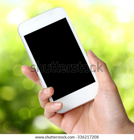  Blank screen mobile phone in hand  on green field background
