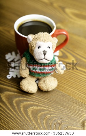 Cup of coffee, snowflake and toy monkey on wooden background.