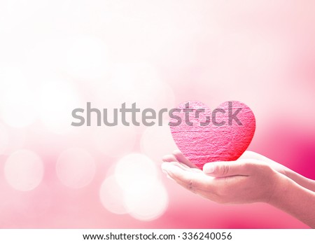 World health day concept: Human hands holding pink heart over blurred nature background