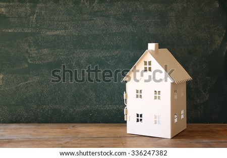 miniature toy house over chalkboard background. room for text