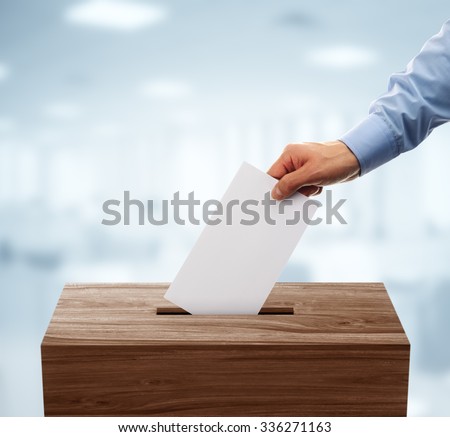Ballot box with person casting vote on blank voting slip Royalty-Free Stock Photo #336271163