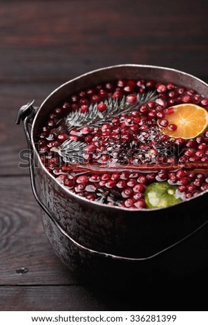 Bubbling cranberry mandarin pomegranate punch or mulled wine in a rustic aged pot