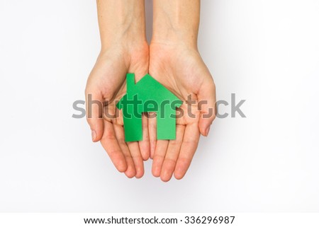 Hands holding paper house figure on white background. Real Estate green house Concept. Ecological building. Top view.