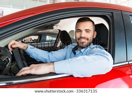 Photo of young man sitting inside new car and smiling. Concept for car rental