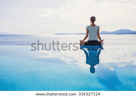 Young woman practicing yoga. Beautiful girl meditating, doing breathing exercises. Harmony, balance, meditation, relaxation, mindfulness, recreation, self care, body care, healthy lifestyle concept Royalty-Free Stock Photo #336327524