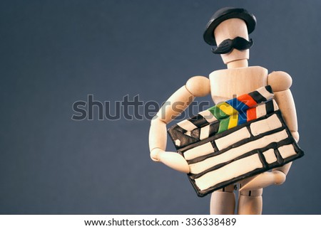 Classic wooden dummy holds a cinema clapper, hat and mustache for true filmmakers.