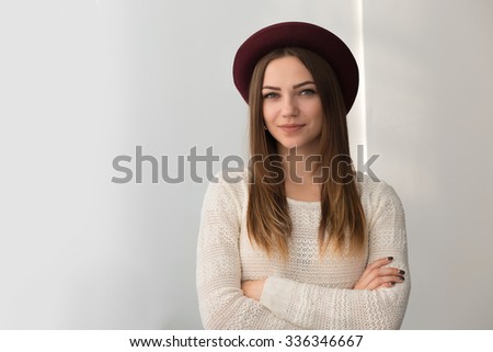 Fashionadle woman in hat. White wall background.