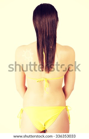 Attractive woman in yellow bikini with sun-shaped sun cream on her body.