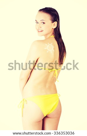 Attractive woman in yellow bikini with sun-shaped sun cream on her body.