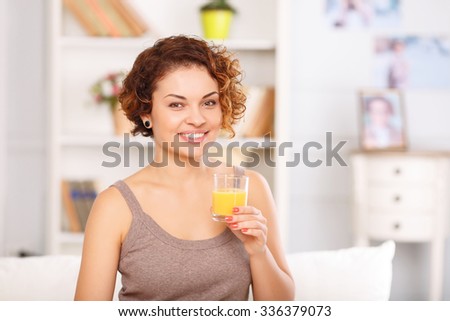 Be a positive thinker. Portrait of pleasant attractive vivacious girl holding glass and drinking juice while having breakfast