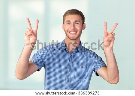 Attractive young man shows a sign of peace or victory