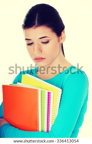 Portrait of young sad female student with workbook.