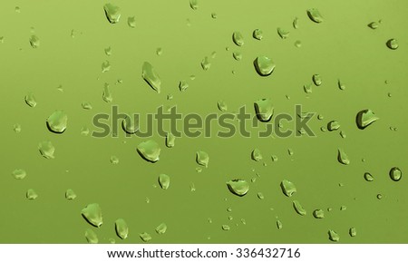 Water drops on glass ice green grass background