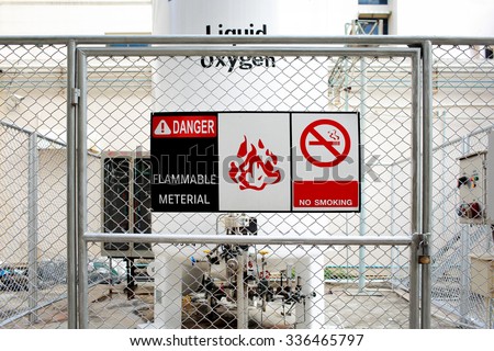 Safety signs warning ( DANGER-FLAMMABLE MATERIAL ) in front of the large Liquid Oxygen tank.