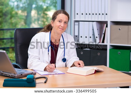 young female family doctor in her office is looking in to the camera