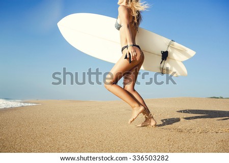 Beauitful young surfer girl running to the waves with her surfboard