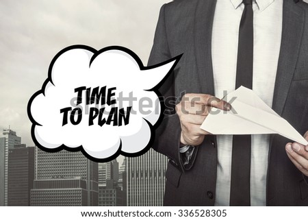 Time to plan text on speech bubble with businessman holding paper plane in hand on city background