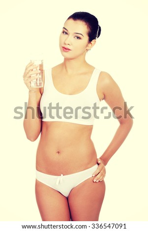 Fit young woman in underwear with glass of mileral water