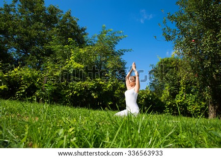 A woman practicing Yoga in the park on a sunny day.
