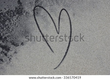 Picture of heart handwritten on golden sand.