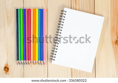 Blank notebook with colour-pencils on wooden table