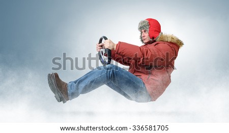 Man driver in red cap with steering wheel. Driving car in snowstorm