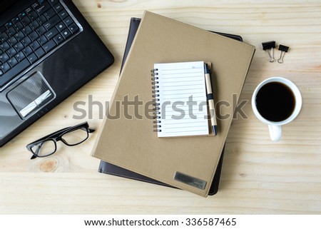 Stack of folder with coffee and laptop on wooden desk