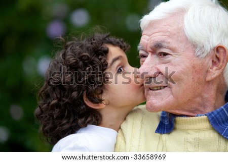 beautiful little girl kissing happily her grandfather