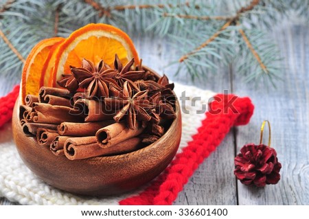 Star anise and cinnamon sticks in a wooden plate on a gray background