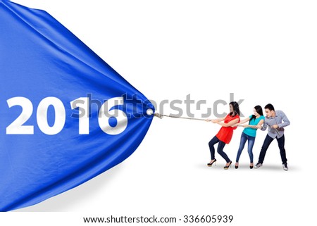 Image of three asian people work together to pull a big banner with numbers 2016, isolated on white background